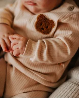 Infant wearing a soft beige knitted outfit