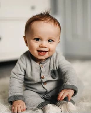 Smiling infant wearing a soft gray outfit