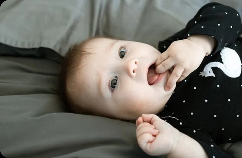 Newborn resting comfortably in a soft black outfit