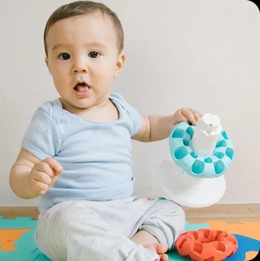 Happy baby sitting and playing with colorful toys